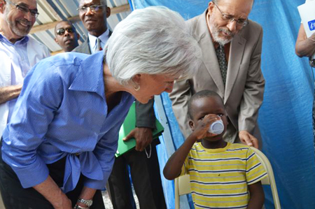 HHS Secretary Sebelius mixes and provides oral rehydration for a child with cholera at the GHESKIO center in Port-au-Prince, Haiti. With Dr. Bill Pape (left), Director of GHESKIO. Credit: Photo by Jean Jacques Augustin.