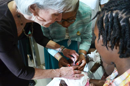 HHS Secretary Sebelius and Haitian Minister of Health Florence Guillaume administer the pentavalent vaccine to a child at the launch of a nationwide vaccine initiative. Credit: Photo by Jean Jacques Augustin.