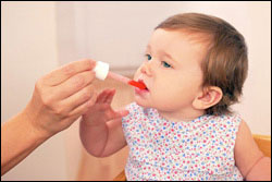 una niña pequeña toma una medicina de mano de un adulto.