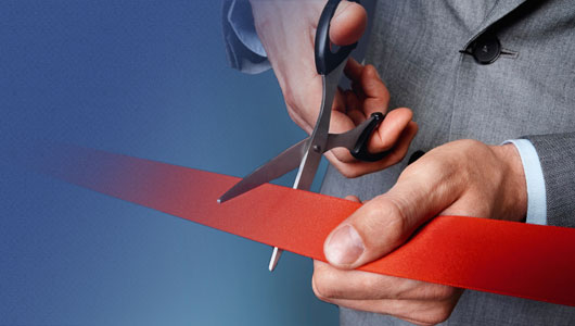 an image of a man in a suit performing ribbon-cutting ceremony