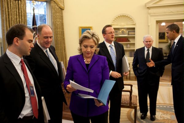 Secretary of State Hillary Clinton confers with Deputy National Security Advisor for Strategic Communications Ben Rhodes, and Deputy National Security Advisor Tom Donilon, as President Barack Obama talks with Press Secretary Robert Gibbs, and Secretary of Defense Robert Gates in the Oval Office, prior to the announcement of the New START Treaty, March 26, 2010. 
