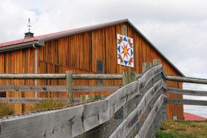 This horse barn's siding is made of telephone poles! The quilt block is called 'summer star flower' and honors a family member's Pennsylvania Dutch heritage. Photo by Ann Cameron Siegal
