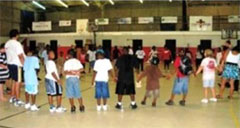 Children in Action Sports Club participants standing in a circle in a gymnasium.