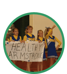Image of young cheerleaders holding a sign that says Healthy Armstrong
