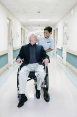 Fotografía de una enfermera asistiendo a un hombre mayor en silla de ruedas