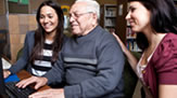 A grandfather learning about the computer with his granddaughters