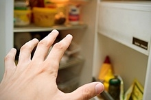 Hand reaching for leftovers in fridge
