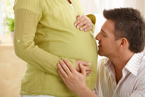 man kissing woman's pregnant belly