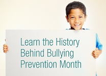 Boy holds sign on history of bullying prevention month.