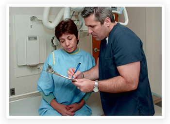 Un médico revisa el papeleo con una paciente antes de realizar una radiografía