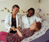 a photo of a doctor and a nurse sanding over a smiling child lying in bed.