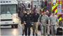 photo of several military men in uniform walking ahead of emergency vehicles.