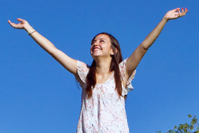 Three young students one reaching for the sky in park