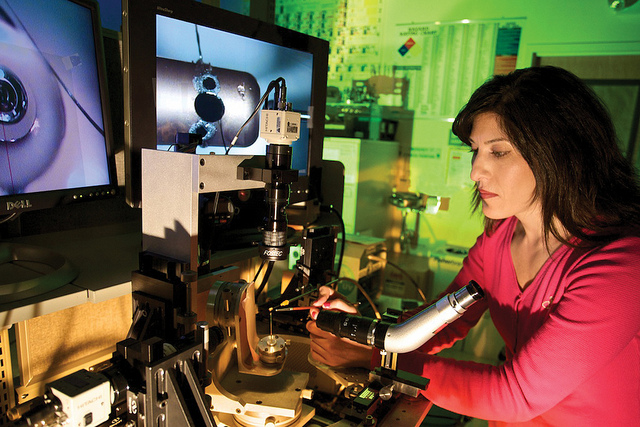 Laida Valdez of Polymers and Coatings attaches a shield to a target. Using a cat whisker, Valdez applies an ultraviolet curing epoxy to attach the shield.