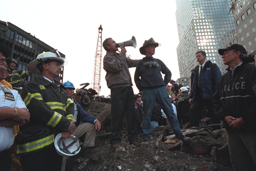 Standing on top of a crumpled fire truck with retired New York City firefighter Bob Beckwith, President George W. Bush rallies firefighters and rescue workers Friday, September 14, 2001, during an impromptu speech at the site of the collapsed World Trade Center towers. 