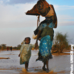 Refugee carrying water and walking with a child