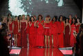 Celebrity women from The Heart Truth's 2011 Fashion Show wearing designer red dresses holding on to each other and clapping at the end of the 2011 fashion show.
