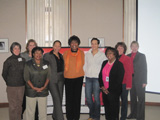 Nine women from the 2009 Buffalo Champions stand in front of a Heart Truth display.