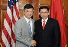 Secretary Locke and MinisterChen shake hands, with U.S. and Chinese flags in the background.