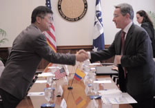 Locke and Uribe shake hands across the conference table. Click for larger image.