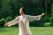 A woman practices Tai Chi outside.