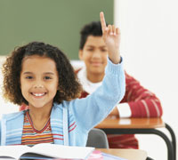 Photo: Girl in classroom, raising hand
