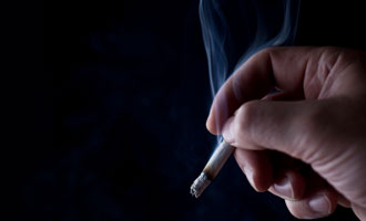 picture of person holding smoking cigarette depicting asthma trigger - SHS