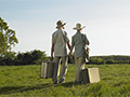 Senior couple in field with suitcases, tips on how to determine where to retire