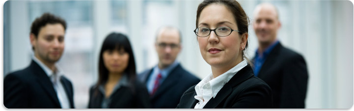 Four professionals, shown the background, with a studious concerned looking woman staring forward