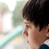 Photo of a young boy looking out a window.