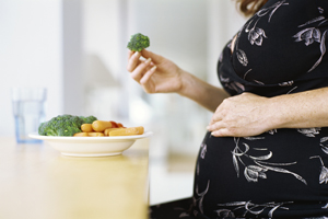 a pregnant woman eating veggies