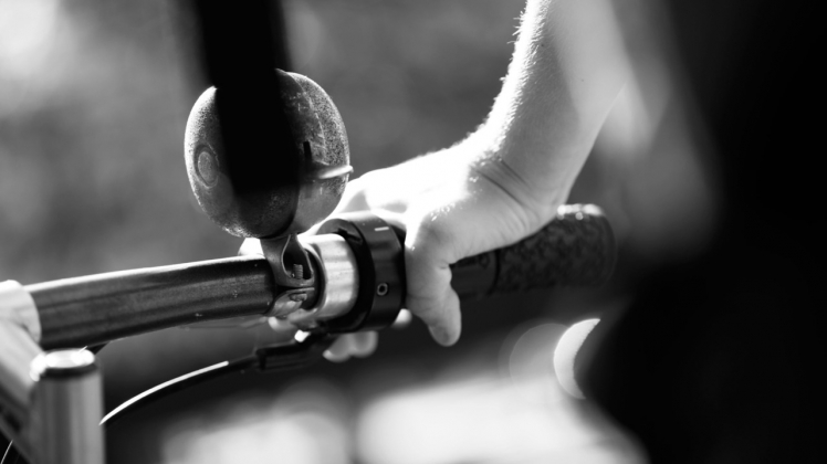 Black and white photo of person grabbing handlebars of bicycle