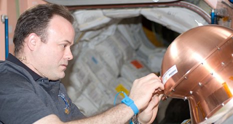 Expedition 28 Flight Engineer Ron Garan applying copper tape to exposed activation ports on the ReEntry Breakup Recorder. (NASA)
