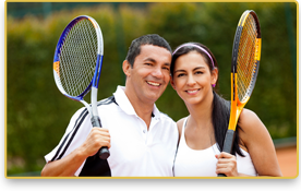 Una pareja sonríe mientras sostienen sus raquetas de tenis