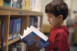 Niño lee libro en una biblioteca