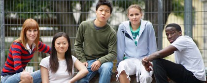 Photograph of a diverse group of teens sitting together and smiling.