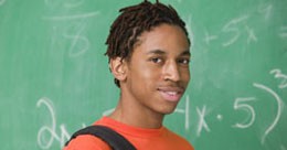 Photograph of a young African American man standing in front of a chalkboard