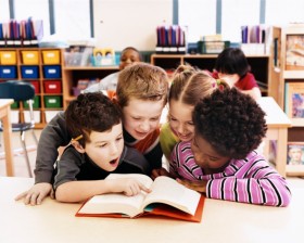 Four kids looking at a book
