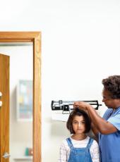 Fotografía de una enfermera midiendo la estatura de una niña