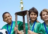 Three soccer players holding up a trophy