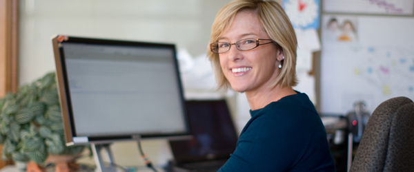 A smiling woman sitting at a computer