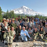 Secretary Ken Salazar and more than 70 Mount Rainier National Park Service employees and volunteers in foreground; Mount Rainier and blue skies in background.