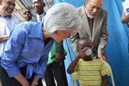 HHS Secretary Sebelius mixes and provides oral rehydration for a child with cholera at the GHESKIO center in Port-au-Prince, Haiti. With Dr. Bill Pape (left), Director of GHESKIO. Credit: Photo by Jean Jacques Augustin.