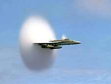 An F/A-18 Hornet aircraft flying through a white cloud