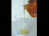 Orange liquid is poured into a clear glass container