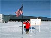 A woman holds an American flag while standing at the South Pole