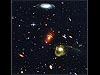 A jumble of galaxies including a yellow spiral galaxy, a young blue galaxy and several smaller red galaxies