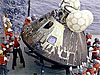 Ship's crew moving an Apollo capsule out of the water to the ship's deck