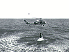 A helicopter pulls a Mercury capsule from the ocean