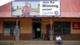 A woman sits beneath a recruiting billboard for the National Union of Mineworkers (NUM) near Rustenburg in the North West province, October 13, 2012. 